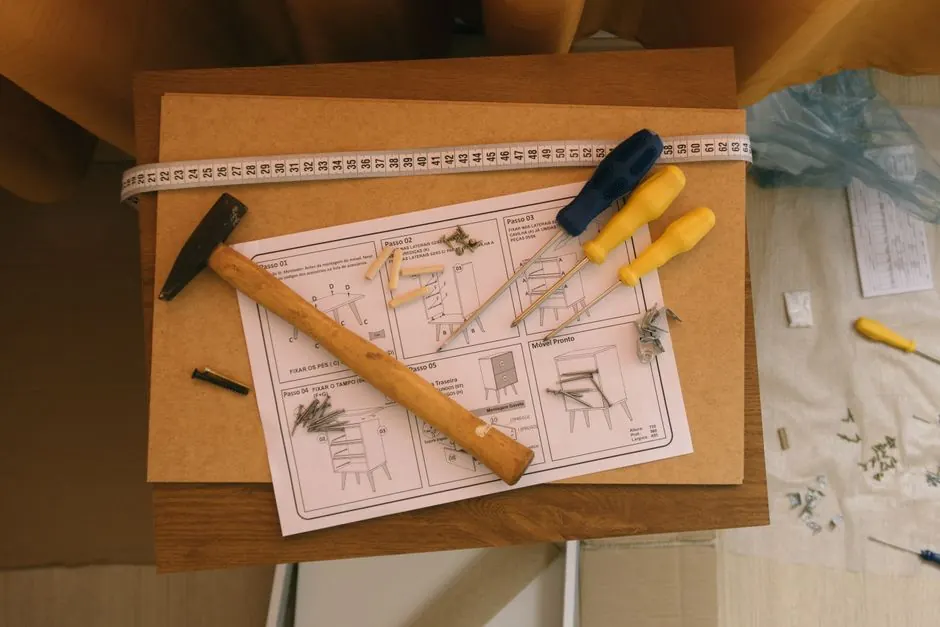From above of paper instruction helping to assemble furniture with screwdrivers and hammer on top